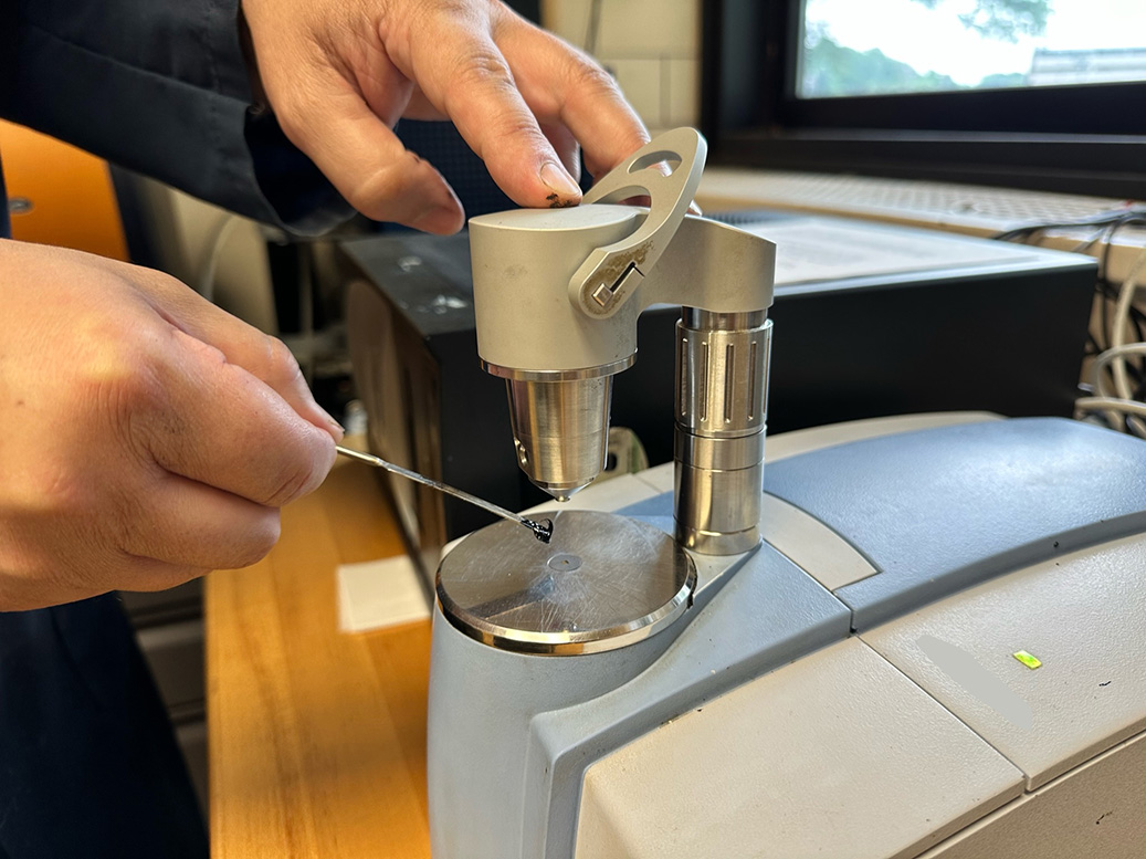 A thimble sized sample of asphalt binder being tested under the microscope of the Fourier Transform Infrared device in an asphalt laboratory.